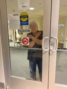 Nurse showing love by crossing arms through window during COVID19 pandemic